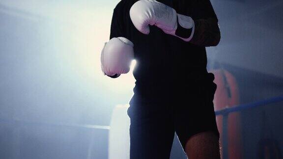 拳击场内的拳击手戴着拳击手套在戏剧性的灯光下待命