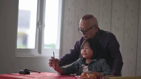 亚洲华人小女孩向她的祖父学习写中国书法