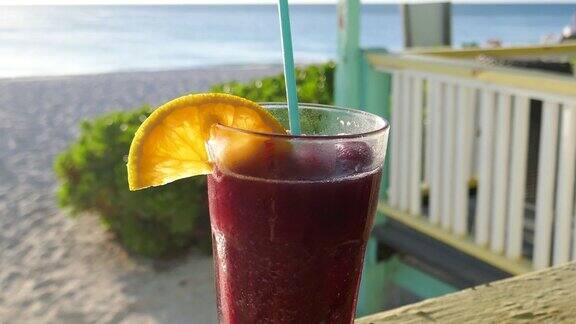 热带清爽冷冻水果饮料在饮用杯柠檬角和海滩度假胜地的焦点在背景