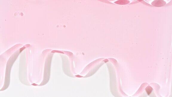 粉红色透明化妆品凝胶液与分子泡沫流动在平原白色表面微距镜头