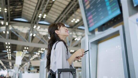 一名亚洲妇女在机场候机厅查询航班时刻表