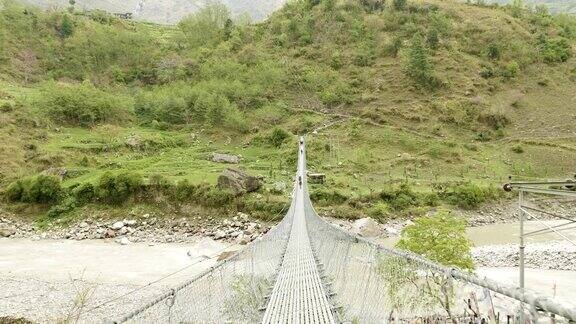 背包客在尼泊尔河上的吊桥上行走Manaslu电路长途跋涉