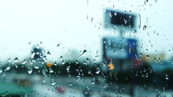 4K:雨滴落在窗玻璃上交通背景中的建筑物