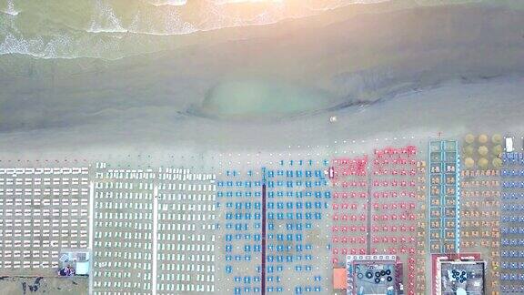 太阳升起时在罗马尼奥拉里维埃拉的沙滩伞和沙滩椅上飞过