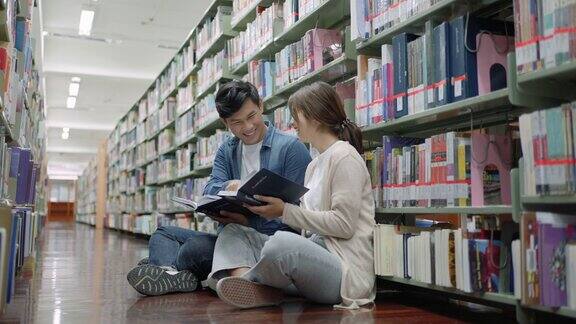 聪明的亚洲男女大学生读书之间的书架与校园图书馆的拷贝空间