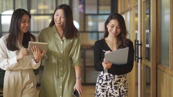一群亚洲华人白领女商人在办公室里散步讨论