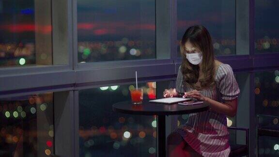 工作到深夜的亚洲女性在家办公时戴着口罩使用平板电脑