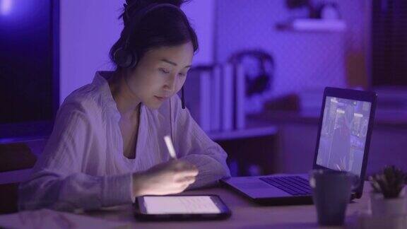 年轻的亚洲女性用笔记本电脑与在家工作到很晚的男同事进行虚拟会议