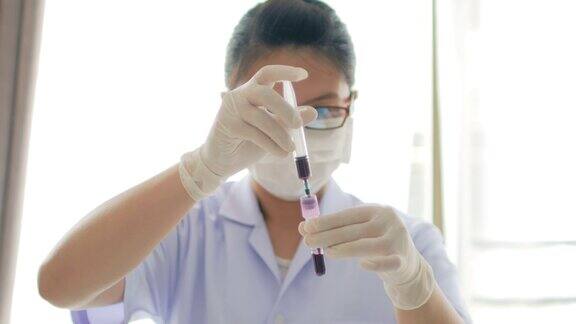 女医生医疗技术员使用红色试管从注射器中注射4k(超高清)血液