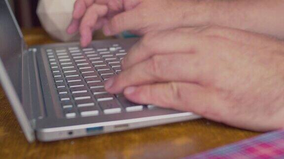 手在笔记本电脑键盘上打字特写浅景深