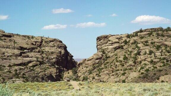 在阳光明媚的天空下怀俄明州的两个岩石悬崖之间有一条小路