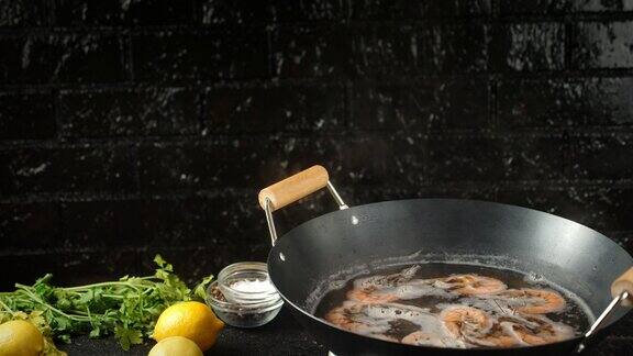 用平底锅盛上热水煮虾配上柠檬和香草