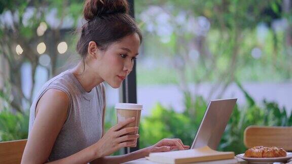 有吸引力的年轻亚洲女性女性数字游牧自由职业者坐在咖啡馆和打字在笔记本电脑上工作在线亚洲女性工作笔记本电脑在咖啡馆休闲生活方式工作