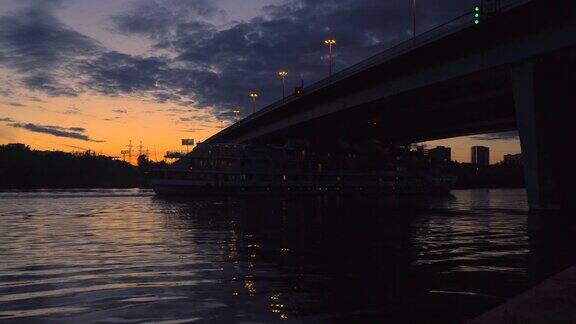日落时分一艘船在桥下航行可以看到这座城市