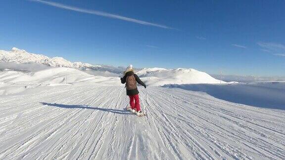 女士滑雪板在一个风景优美的滑雪斜坡与雪山的壮丽景色