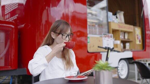 一名亚洲妇女正在使用电子平板电脑咖啡师正在为她端上一杯热拿铁