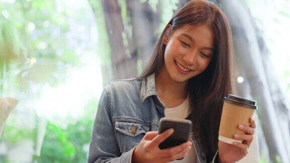 年轻的亚洲美女使用智能手机在咖啡厅咖啡厅打字写短信在手机上网上购物转账支付网上银行