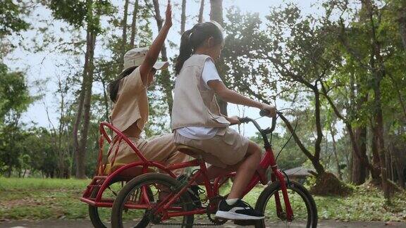 小女孩和姐姐一起骑着三轮车和载货自行车