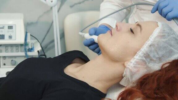 幸福的女人在侧面躺在温泉和接受一个程序在美容诊所做面部年轻化手术