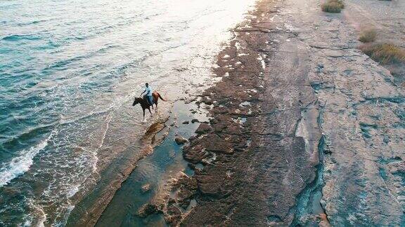 日落时分海滩上骑马的男人