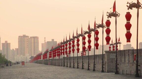 中国陕西西安日落时古城墙上的龙旗和灯笼