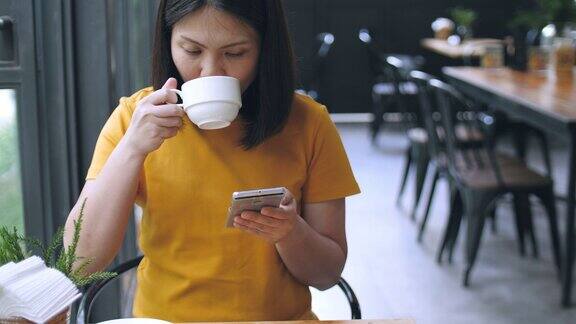 一个女人在咖啡馆边喝咖啡边用手机