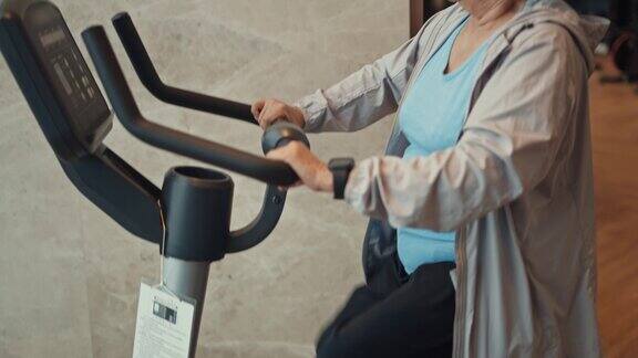 亚洲成熟女性在健身房锻炼自行车倾斜向下