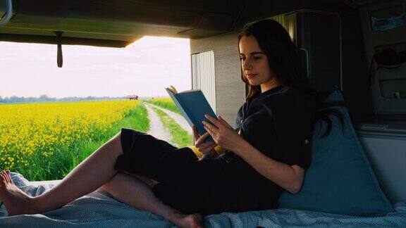 女警官在一辆停在油菜籽田旁的露营车的小木屋里看书