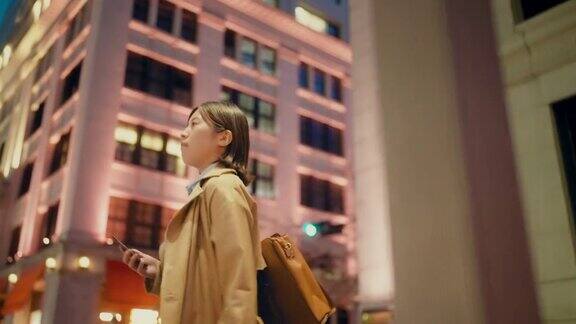 年轻的女商人拿着她的智能手机在城市的金融区通勤