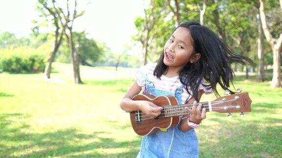 亚洲小女孩在花园里弹奏四弦琴