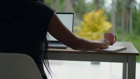 一个女人使用笔记本电脑的后视图