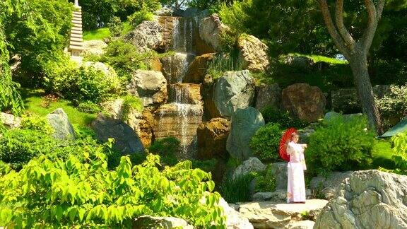 风景在瀑布附近的日本花园中一位穿着和服的美丽女子
