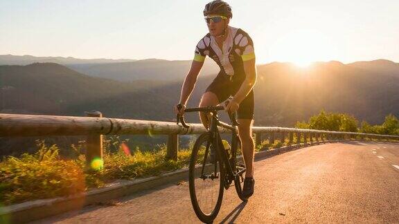 年轻的运动员站在公路上骑自行车被阳光照亮