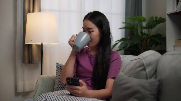 年轻的单身女性用智能手机在客厅的沙发上放松