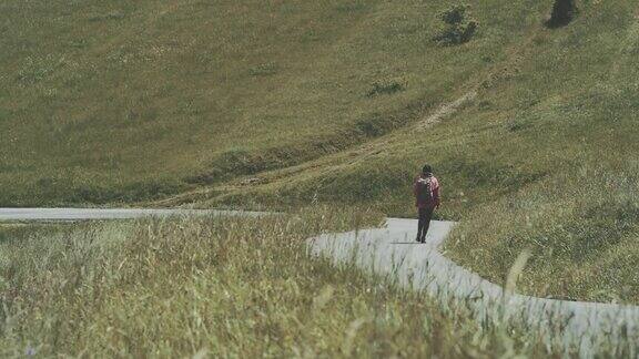 在绿色山丘间行走的女人