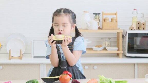 童趣女孩在厨房手捧牛油果有机食品健康生活方式
