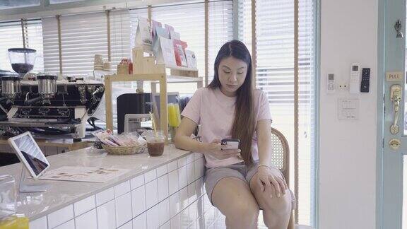 一位年轻的亚洲女子大清早坐在吧台边喝咖啡