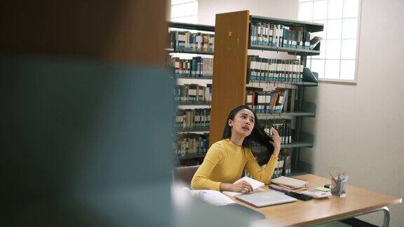 前景里的女人正在看书年轻的亚洲女性带着紧张的情绪在现代图书馆里阅读有教育观念的人