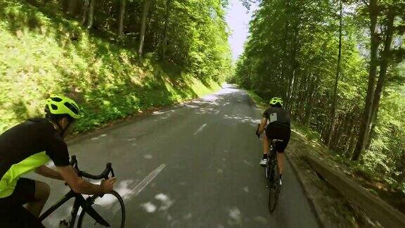 在一个阳光明媚的日子里骑自行车的人沿着山路下行