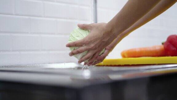 一名妇女用手清洗菜单沙拉的蔬菜