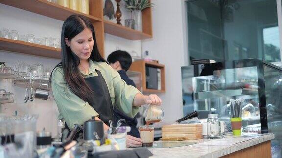 亚洲女咖啡师在他的咖啡店里做咖啡杯