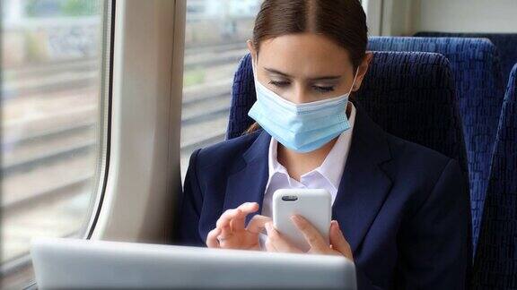 戴着面具在火车上工作年轻女子的手提电脑和手机