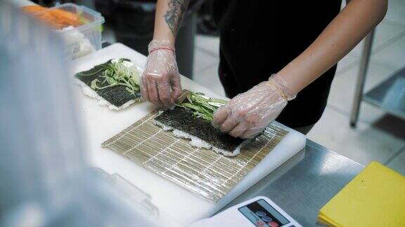寿司日本的食物烹饪烹饪寿司师傅用竹席制作寿司卷寿司配奶油芝士、黄瓜、米饭、海苔特写镜头在餐厅的厨房