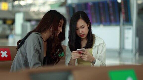 两名亚洲女性在机场使用智能手机