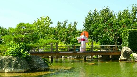 穿着和服的女人在公园的桥上走过池塘