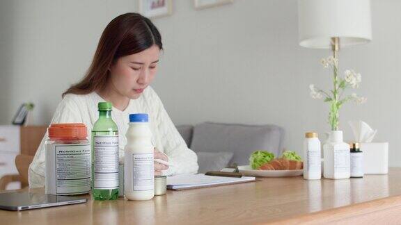 女性专业营养学家阅读食品包装上的营养成分标签在家里把数据写在文件上