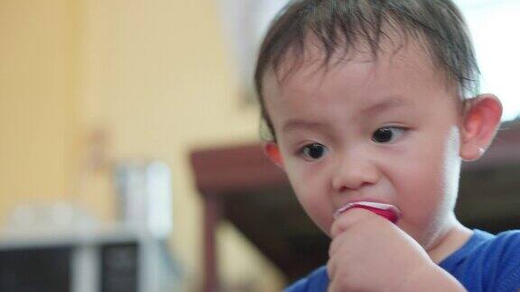 亚洲小男孩喜欢在家里玩耍时牵着别人的手吃草莓红果冻