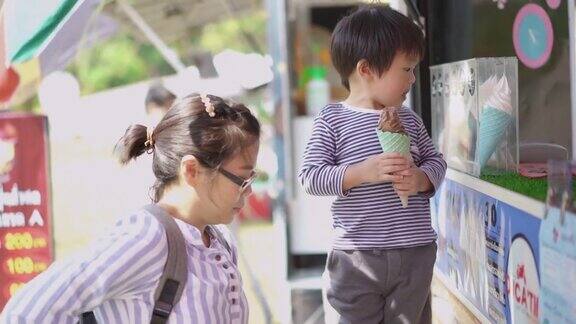 亚洲小男孩和妈妈在冰淇淋餐车吃冰淇淋