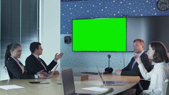团队员工在会议室交谈墙上的模型用绿屏显示