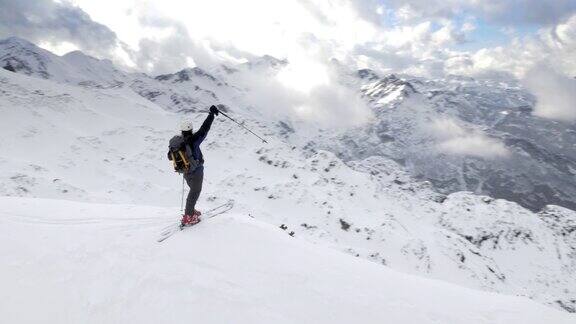 空中滑雪旅行者在征服的山顶举起双手